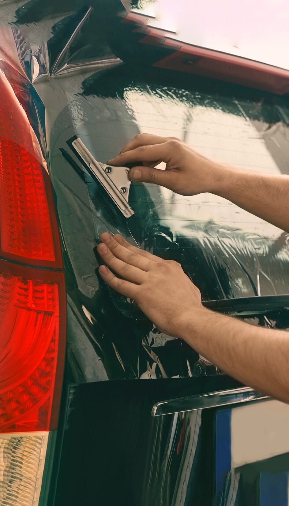 worker applying tinting foil onto car window
